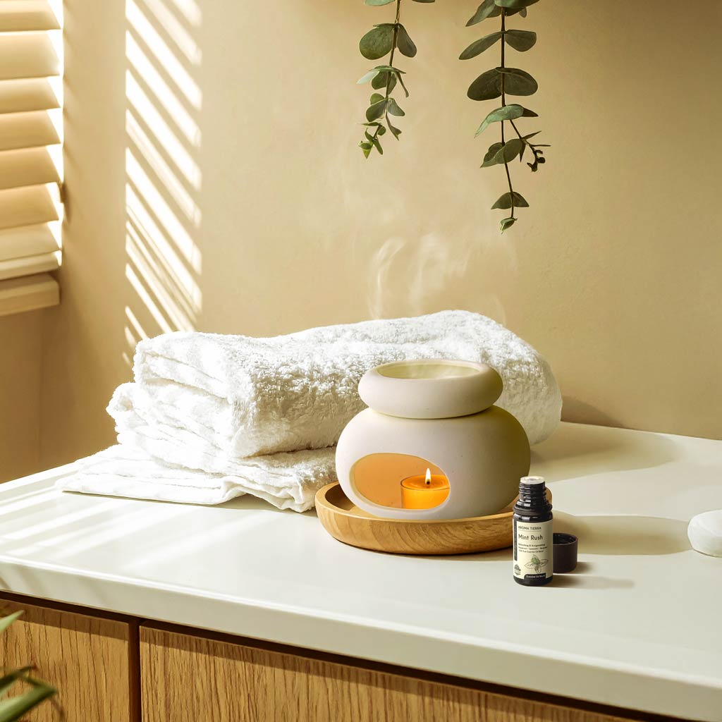 Aroma Tierra Lona ceramic candle burner with Mint Rush essential oil on bathroom counter with eucalyptus and towels