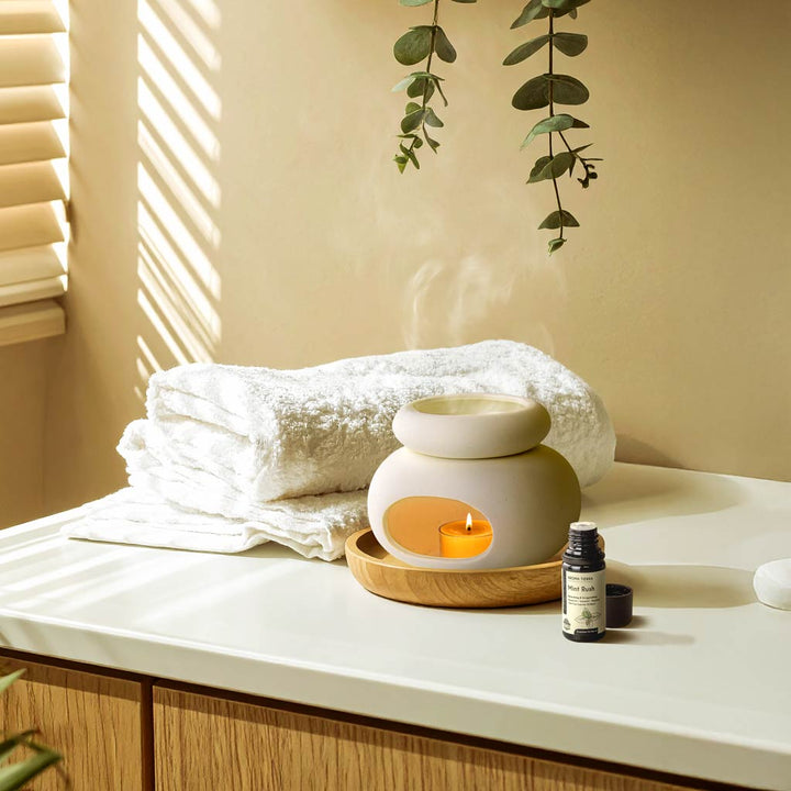 Aroma Tierra Lona ceramic candle burner with Mint Rush essential oil on bathroom counter with eucalyptus and towels